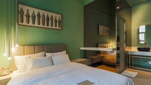 Ein Hotelzimmer mit Bett, Nachttischen, einem Spiegel und einem Badezimmer mit Waschbecken und Spiegel.