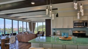 Een moderne keuken met een groot eiland, barkrukken en uitzicht op de stad.