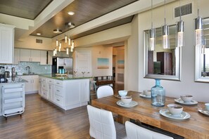 A modern kitchen with white cabinetry, a central island, and pendant lighting.