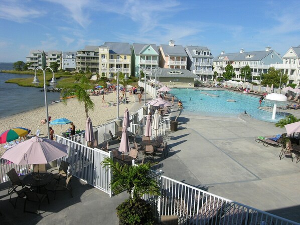 A resort with a swimming pool, beach area, and multiple buildings with balconies.