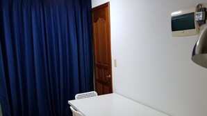 A small room with a white table and two chairs, a wooden door, and a wall-mounted TV. - Galaxy Gangnam 2 (Seoul)