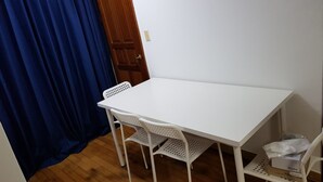 A small room with a white table and two white chairs, a wooden door, and a blue curtain. - Galaxy Gangnam 2 (Seoul)