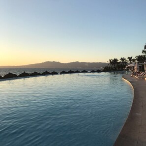 Relax by the serene pool, surrounded by lounge chairs and umbrellas, with breathtaking mountain views.