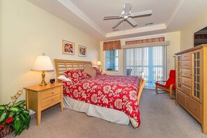 A bedroom with a bed, nightstand, lamp, dresser, and a window with curtains.