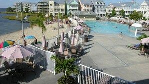 A resort with a swimming pool, beach area, and multiple buildings with balconies.