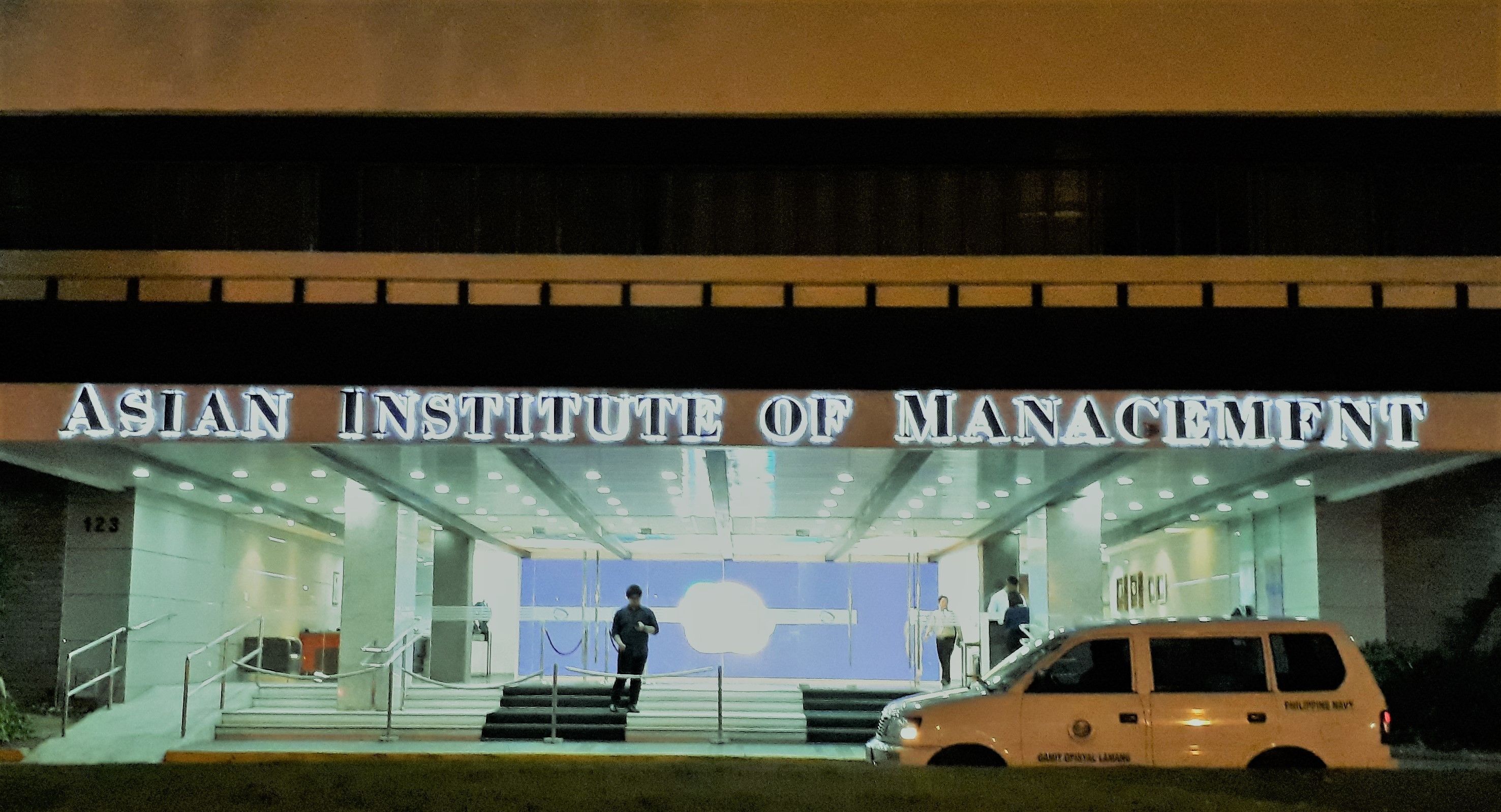 La entrada al Instituto Asiático de Gestión, con un vehículo estacionado frente a ella.