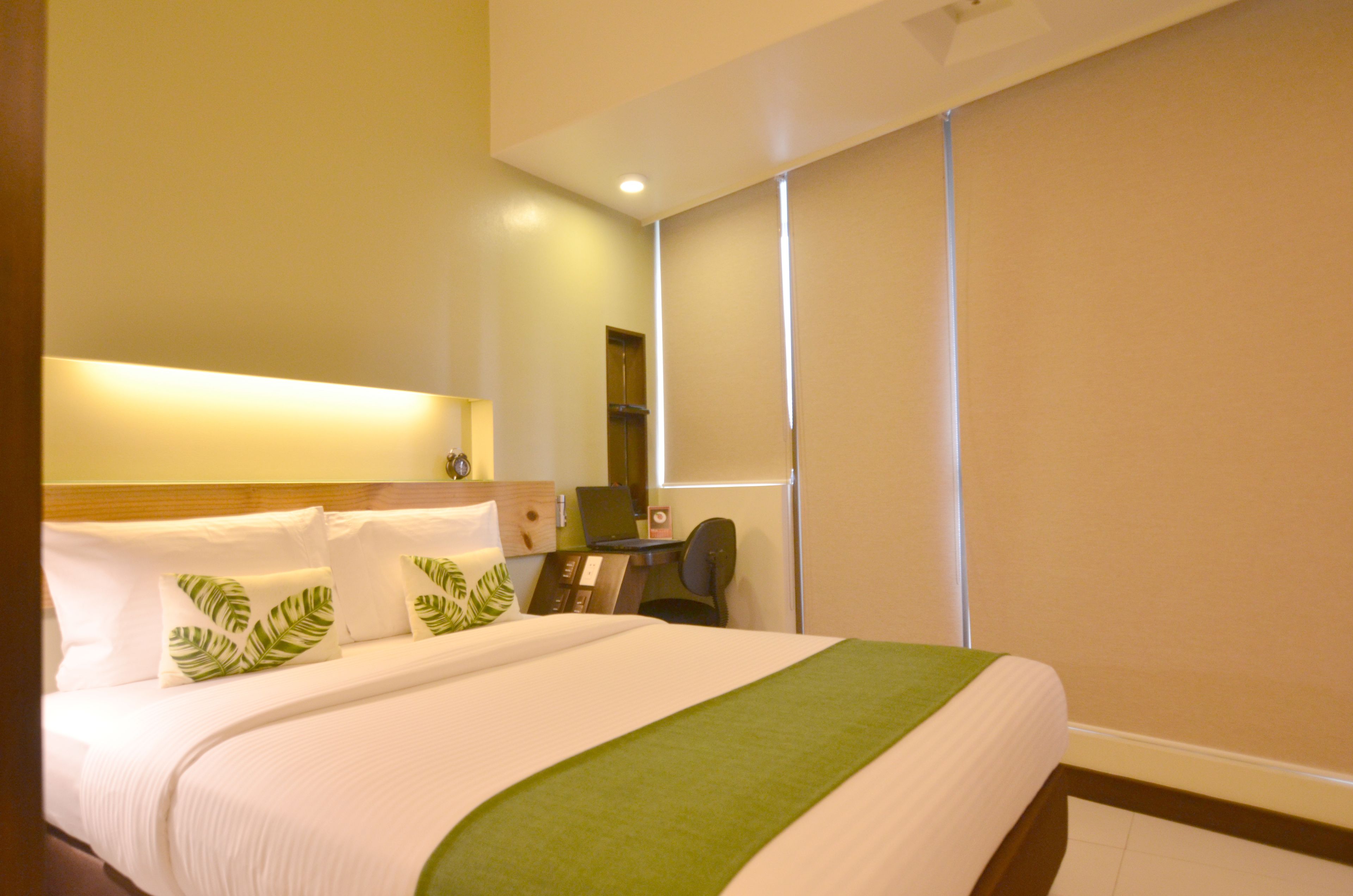 A hotel room with a bed, a desk, and a chair.