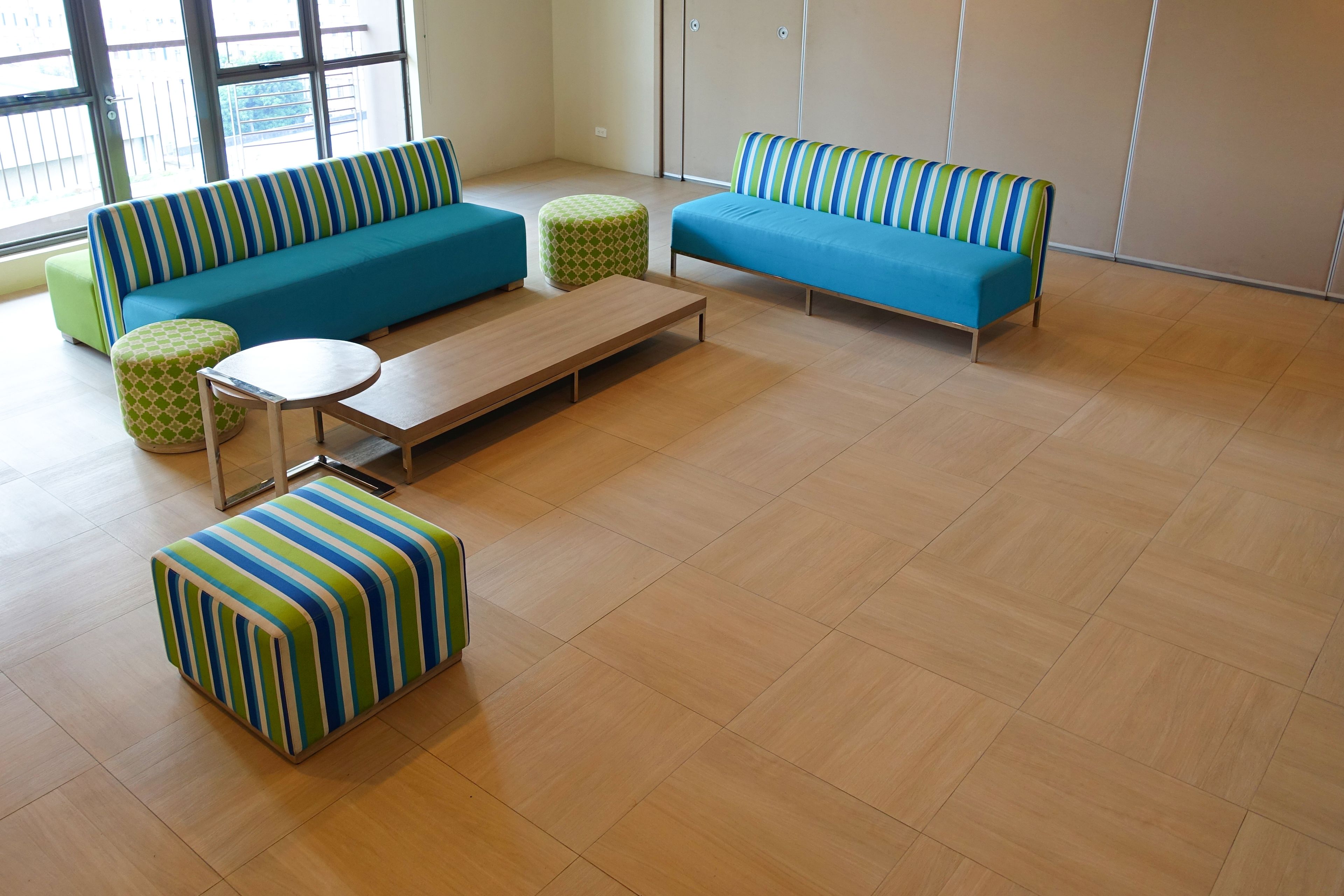 Un salon moderne avec un canapé bleu, une table basse en bois et des poufs à rayures.