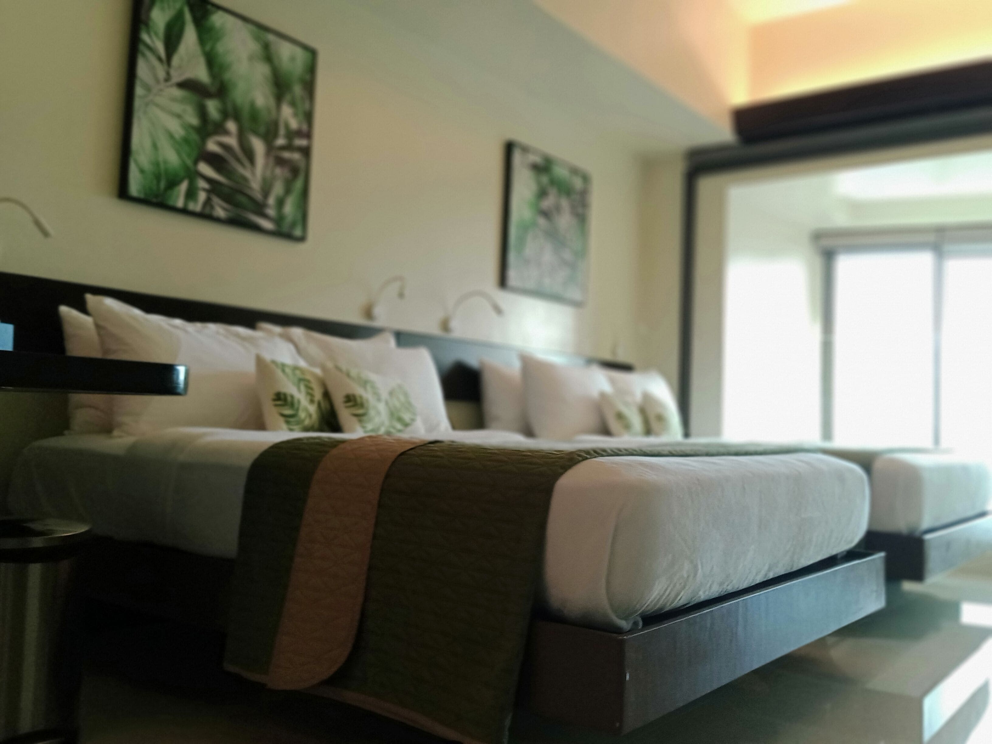 A modern hotel room with a large bed, a bedside table, and a window with a view.