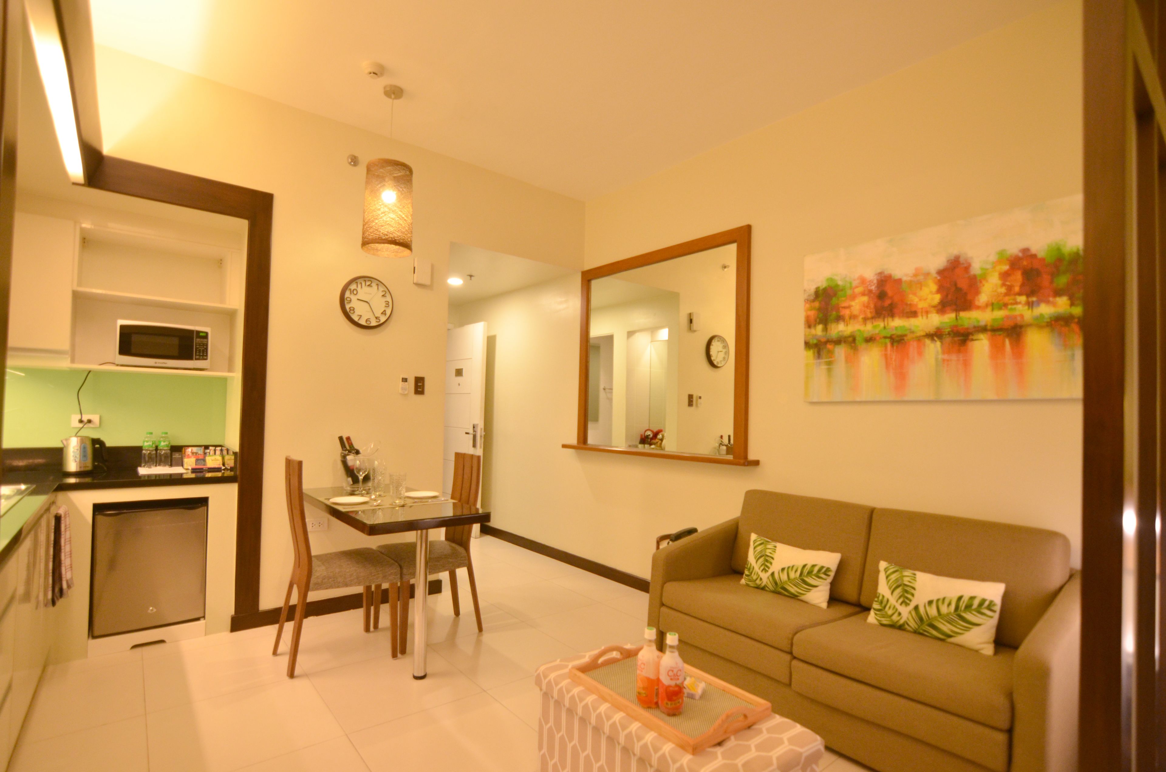 A compact living space with a dining area, kitchenette, and a sofa with decorative pillows.