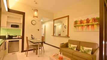 A compact living space with a dining area, kitchenette, and a sofa with decorative pillows.