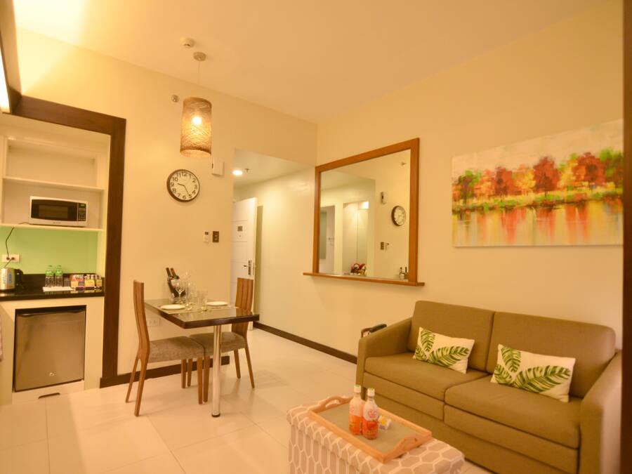 A compact living space with a dining area, kitchenette, and a sofa with decorative pillows.
