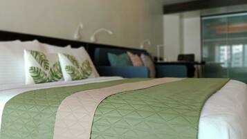 A hotel room with a bed, a nightstand, and a view of the outside.
