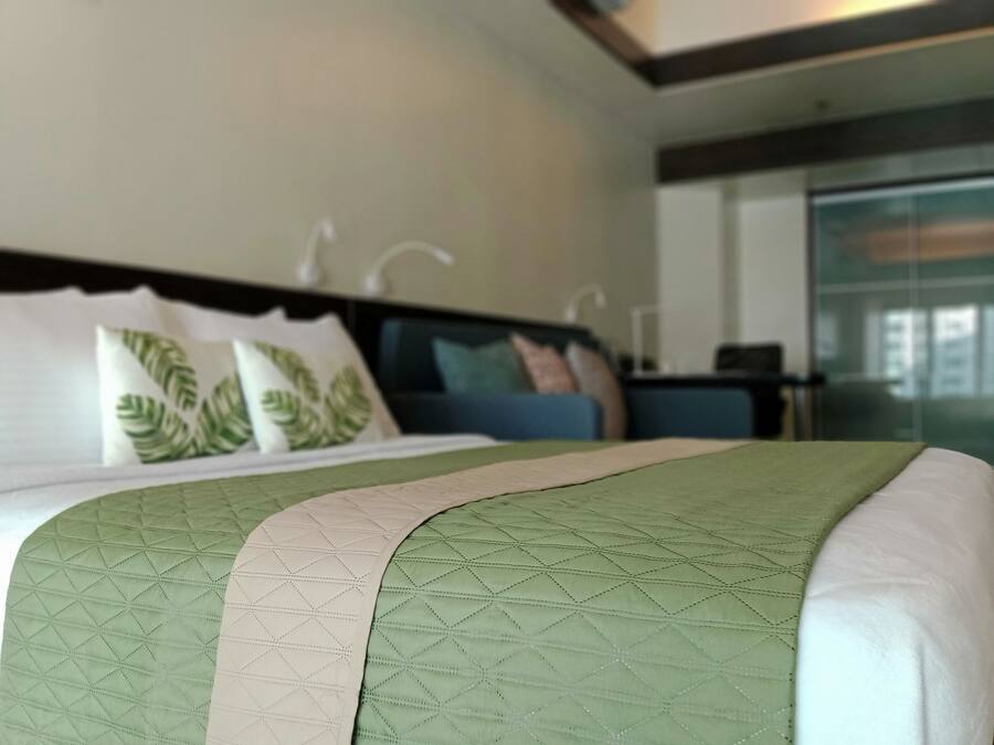 A hotel room with a bed, a nightstand, and a view of the outside.