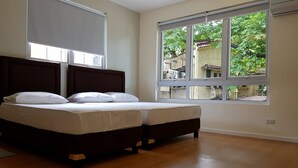 Un dormitorio con un ventanal grande, una cama y una mesita de noche.