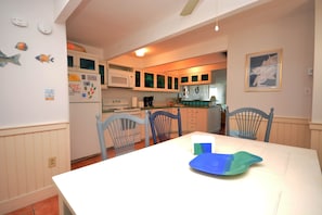 A kitchen with white cabinets, a microwave, and a dining table with chairs. - Bright, colorful 3 bedroom oceanfront townhouse with WiFi, fun decor, and two decks with fabulous ocean views located midtown and only steps to the beach! (Ocean City)