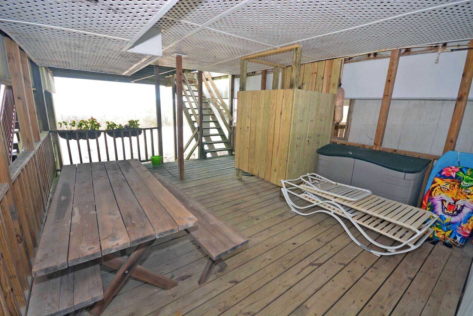 A wooden deck with a picnic table, a metal bench, and a staircase leading to a higher level.
