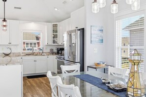 A modern kitchen with white cabinetry, stainless steel appliances, and a dining area with a glass table.