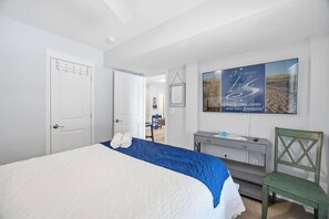 Une chambre à coucher avec un lit, une chaise, une commode et une affiche accrochée au mur.