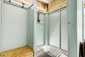 Une pièce avec un banc en bois, une porte en métal et une grille d’aération sur le mur.