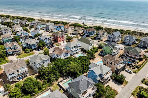 Un quartier résidentiel situé sur la côte, avec des maisons, une plage et une vue dégagée sur l’océan.