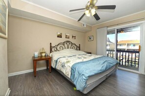 A bedroom with a bed, a nightstand, a ceiling fan, and a view of a balcony. - Cute, stylish 3 bedroom condo with free WiFi and a boat dock located in peaceful midtown right on the bay water and eight blocks to the beach! (Ocean City)