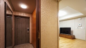 A hotel room with a wooden wardrobe, a television, and a patterned wall. - Gangnam Galaxy Apartment 1 (Seoul)