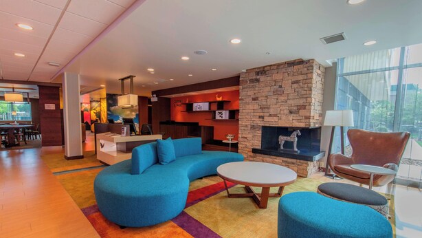 A modern lounge area with a blue sectional sofa, a round coffee table, and a stone fireplace.