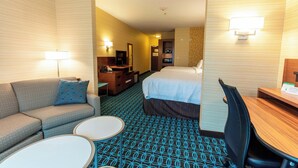 A hotel room with a bed, a sofa, a desk, a chair, and a small table.