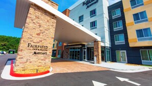 A Fairfield Inn & Suites Marriott hotel entrance with a brick facade, a covered walkway, and a clear sky.