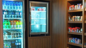 A vending area with a refrigerated display and shelves stocked with snacks.