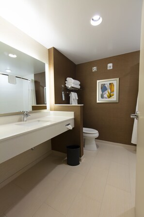 A modern bathroom with a white sink, mirror, and toilet. There is a black trash bin and a towel rack with towels. - Fairfield Inn & Suites by Marriott Atlanta Woodstock (Woodstock)