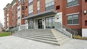 A multi-story brick building with a central entrance, a staircase leading to the ground floor, and a sign indicating 'Montclair Residences'. - Montclair Apartments by Gracen Properties (Montclair)