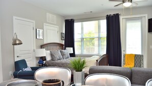 A living room with a sofa, chairs, a dining table with plates, a lamp, and a ceiling fan. - Montclair Apartments by Gracen Properties (Montclair)