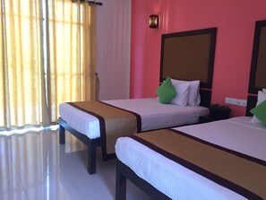 A hotel room with two beds, a large mirror, and a window with curtains.