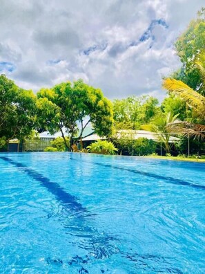 Une piscine d’eau cristalline, entourée d’une végétation luxuriante et d’arbres.