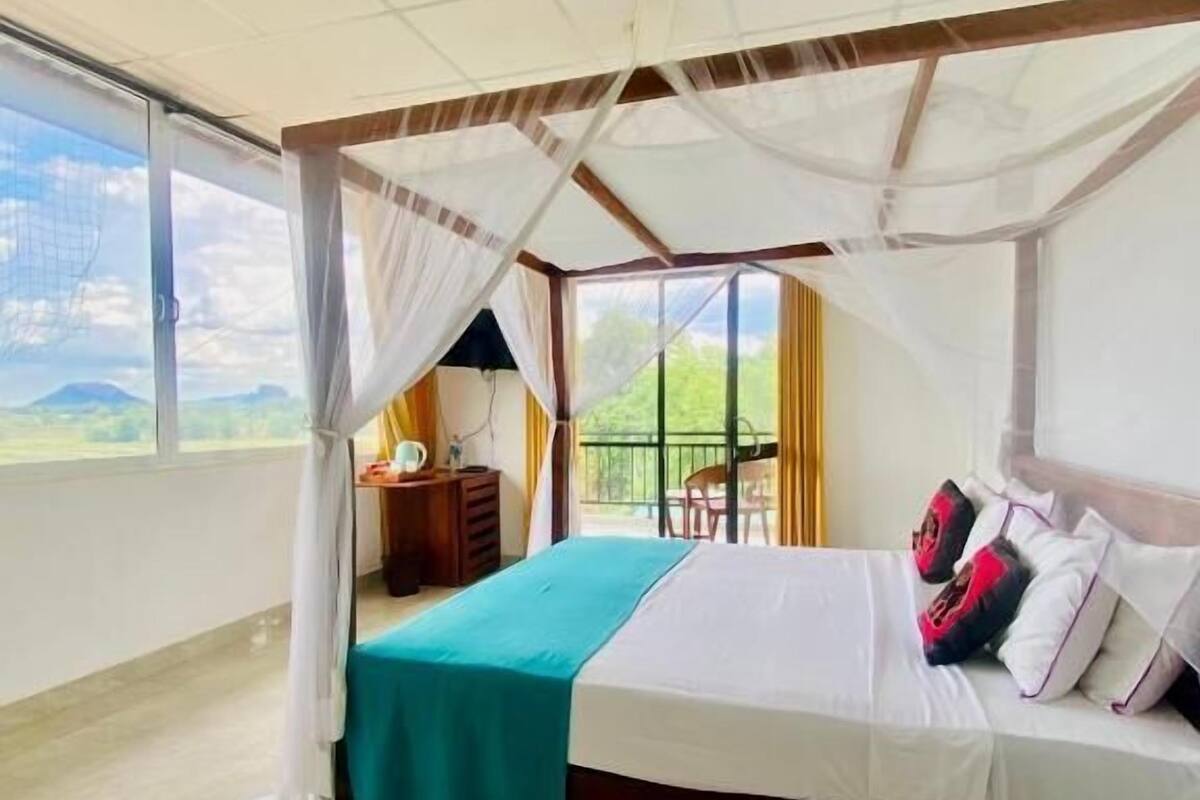 Une chambre à coucher comprenant un lit, une table de chevet, une chaise, une table et une vue sur l’extérieur.