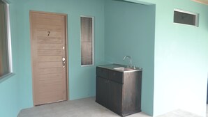 Un bagno piccolo e pulito con una porta di legno con la scritta '7', un mobile scuro con un lavandino e una finestra.