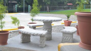 Pátio com um banco de pedra e plantas em vasos.