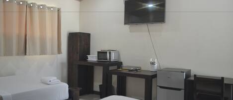 Une chambre d’hôtel avec deux lits, un téléviseur fixé au mur, un four à micro-ondes, un petit réfrigérateur et un bureau en bois.