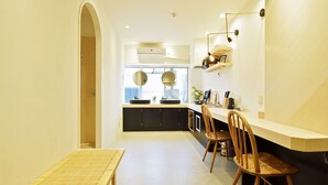 A modern kitchen with a central island, two pendant lights, and a built-in oven. - HOSTEL nid OSAKA (Osaka)