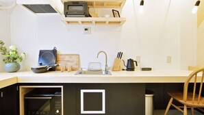A modern kitchen with built-in appliances, a wooden countertop, and a hanging light fixture. - HOSTEL nid OSAKA (Osaka)