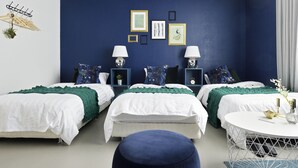 A modern bedroom with three beds, a round table, and a blue accent wall. - HOSTEL nid OSAKA (Osaka)