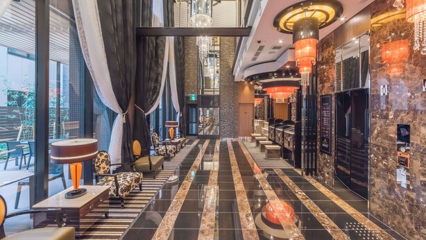 Eine moderne Hotelhalle mit einer langen Rezeption, bequemen Sitzgelegenheiten und einem Kristallleuchter.