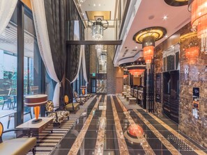 Un vestíbul d'hotel modern amb un taulell de recepció allargat, seients confortables i un penjador de cristall.