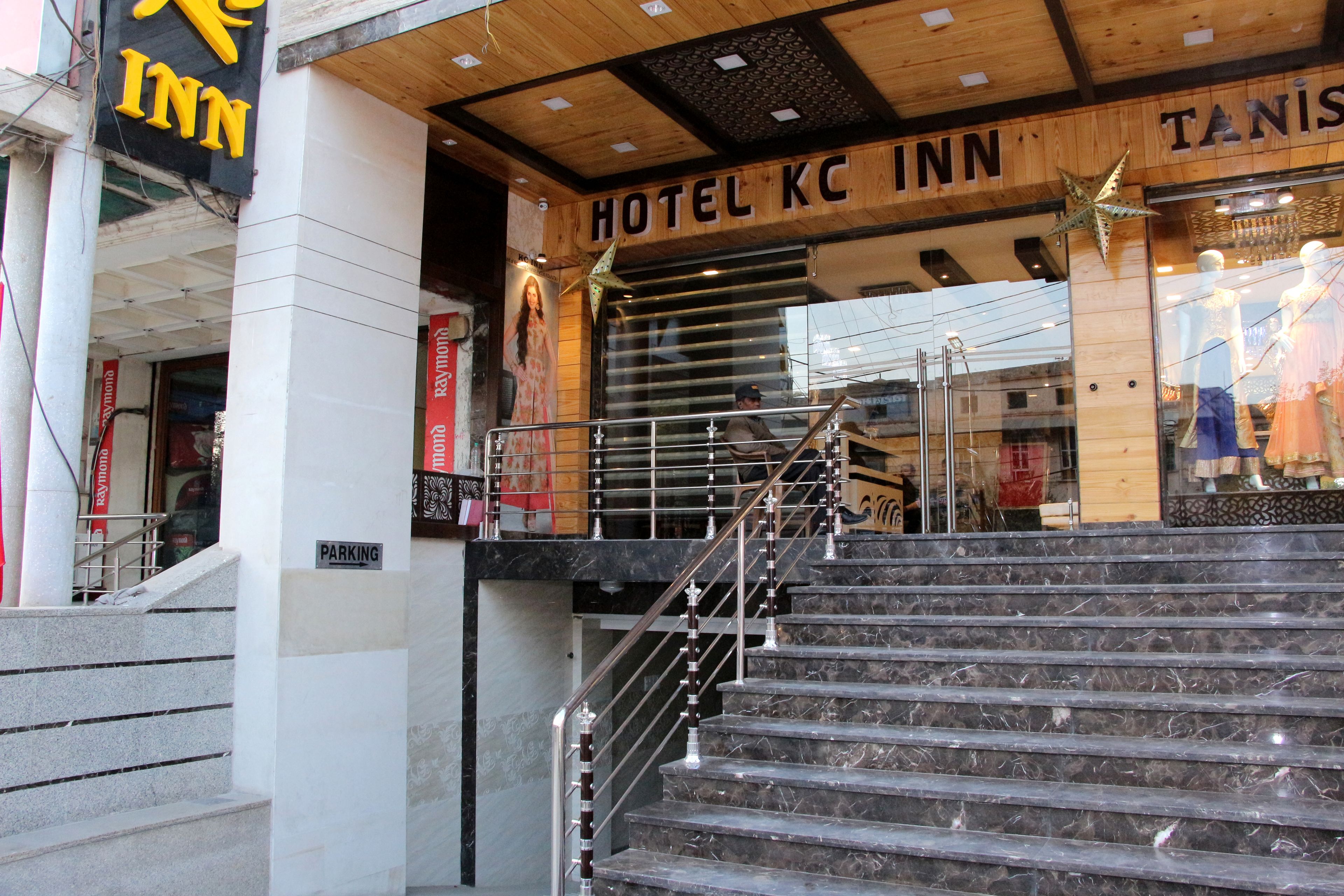 Hotellin sisäänkäynti, jossa on portaikko, joka johtaa aulaan, kyltti, jossa lukee Hotel KC Inn, ja selvästi näkyvä kyltti, jossa lukee PARKKEERAUS.
