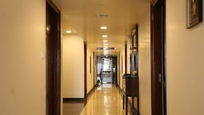 A long, well-lit hallway with wooden doors and a polished floor, leading to a reception area. - Kc Inn (Ajmer)