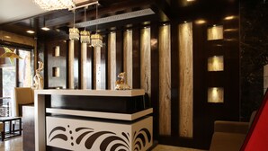 A reception desk with a modern design, featuring a black and white color scheme, decorative elements, and a chandelier. - Kc Inn (Ajmer)