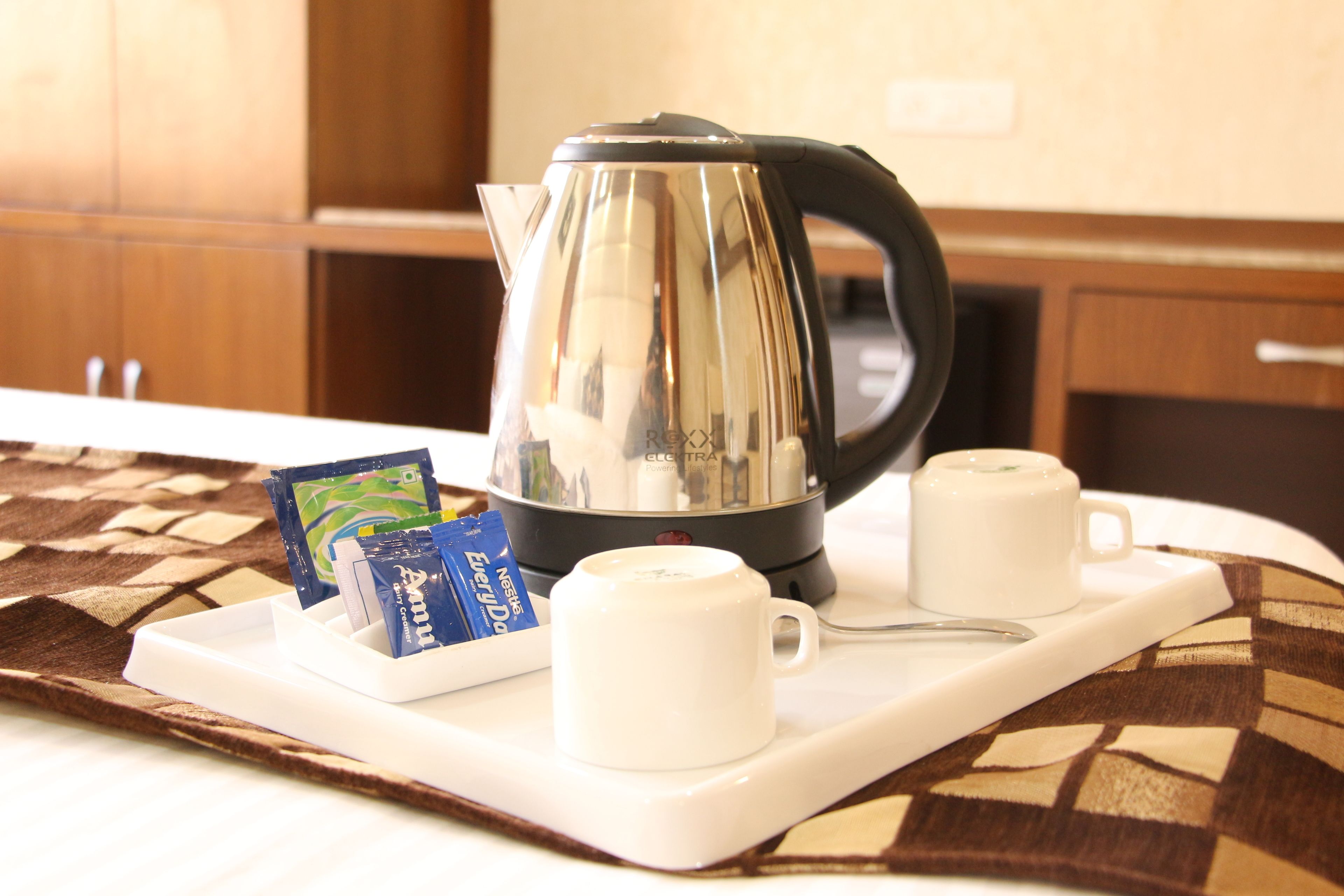 A tray with a kettle, two white cups, and a packet of Nestle EveryDay.