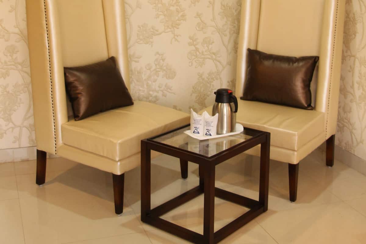 Two leather armchairs with cushions, a small wooden table with a coffee pot, and a floral wallpaper pattern on the wall.